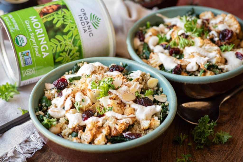 Winter greens bowl with a moringa cashew dressing in a green bowl with a candle.