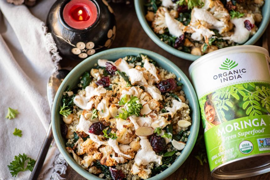 Winter greens bowl with a moringa cashew dressing in a green bowl with a candle.